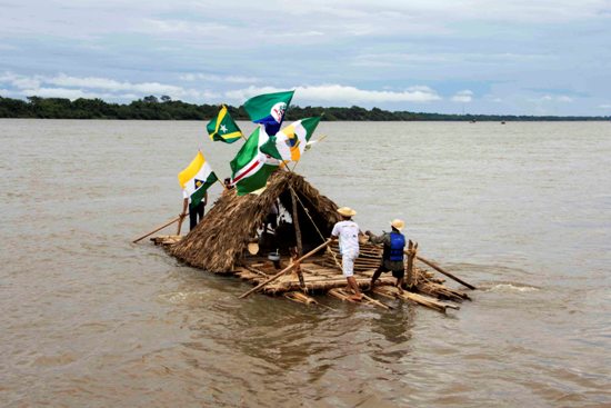 Balsa deixa Imperatriz, desfraldando a bandeira do município, junto com as demais bandeiras de municípios visitados.