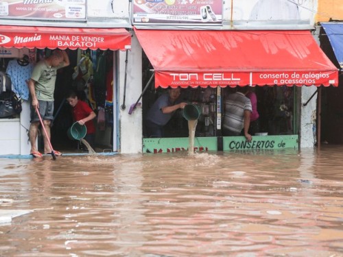 Populares tentam impedir a invasão da água depois da forte chuva que provocou diversos pontos de alagamento (Foto Estadão)